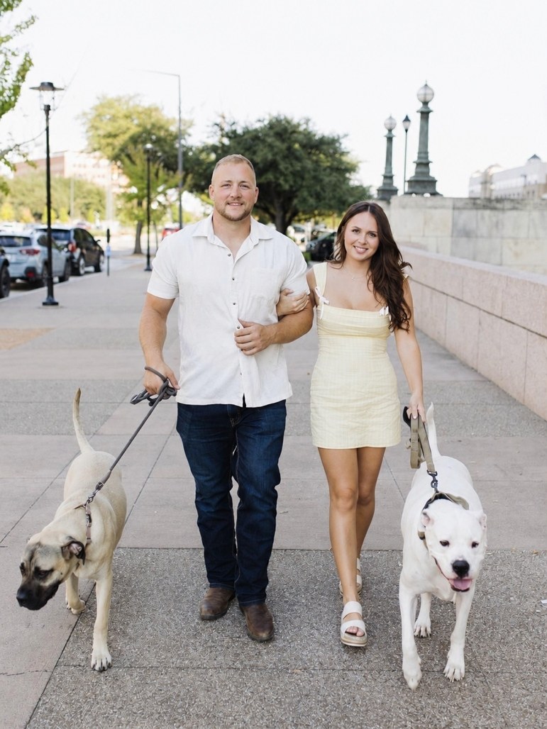 Sierra and Liam Murray walking their two dogs on a tree-lined sidewalk
